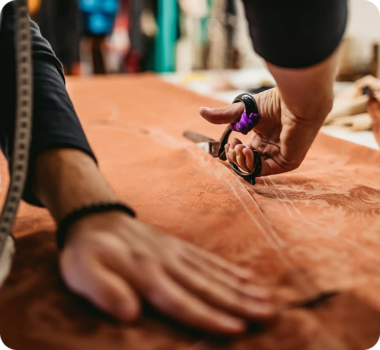A fashion designer cutting fabric with a pair of scissors
