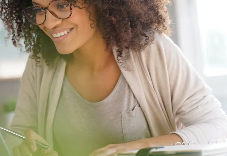 Female lady wearing glasses with a pen in hand working at a desk